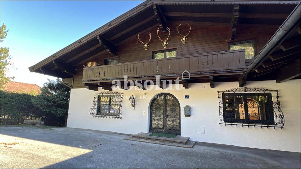 Traditionelle Hausfassade mit Holzbalkon, schmiedeeisernen Fenstergittern und dekorativen Hirschgeweihen.