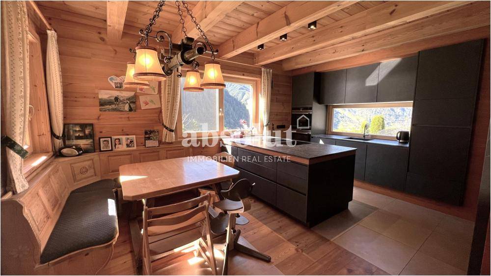 Gemütliche Holzküche im Landhausstil mit moderner Kücheninsel und Essbereich mit Bergblick.