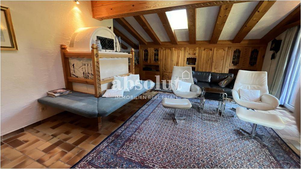 Gemütliches Wohnzimmer mit Holzbalkendecke, Kachelofen und bequemen Sesseln, ideal zum Entspannen.