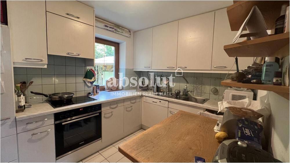 Funktionale Küche mit weißen Schränken, Fliesenrückwand und Fenster mit Blick ins Grüne.