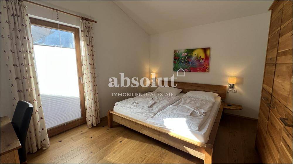 Helles Schlafzimmer mit Doppelbett, Holzboden und Zugang zum Balkon.