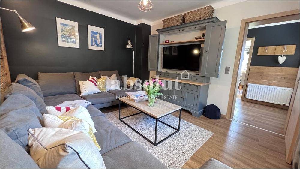 Gemütliches Wohnzimmer mit großem Ecksofa, dunklen Wänden und Holzboden, ideal zum Entspannen.