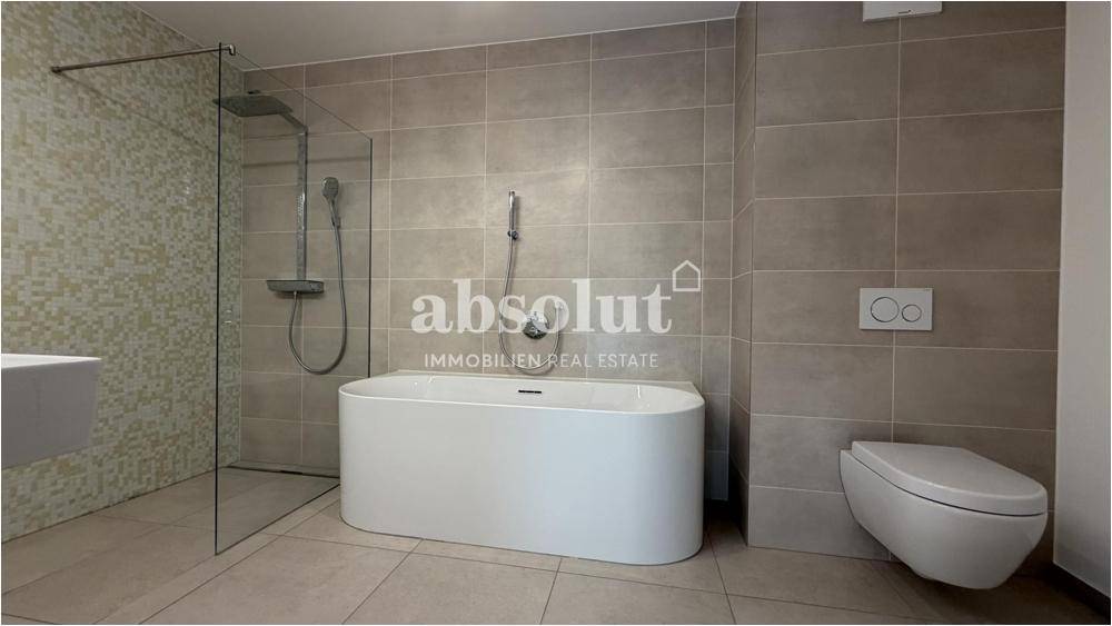 Modernes Badezimmer mit freistehender Badewanne, begehbarer Dusche und Wand-WC.