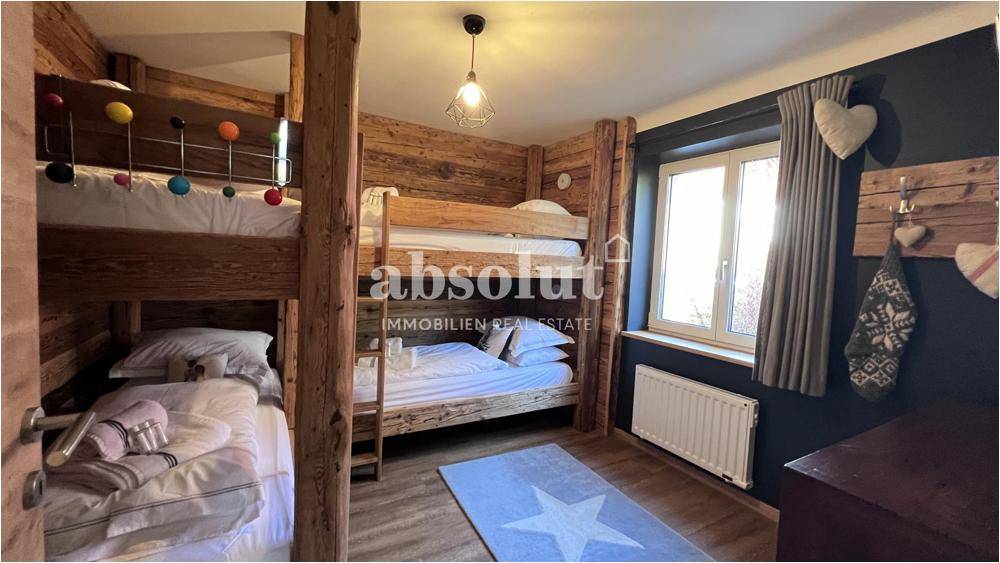 Gemütliches Schlafzimmer mit zwei Etagenbetten und Holzwänden, im alpinen Stil eingerichtet.
