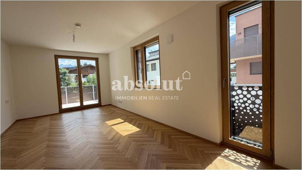 Helles Schlafzimmer mit Fischgrätparkett und Zugang zu einem französischen Balkon.