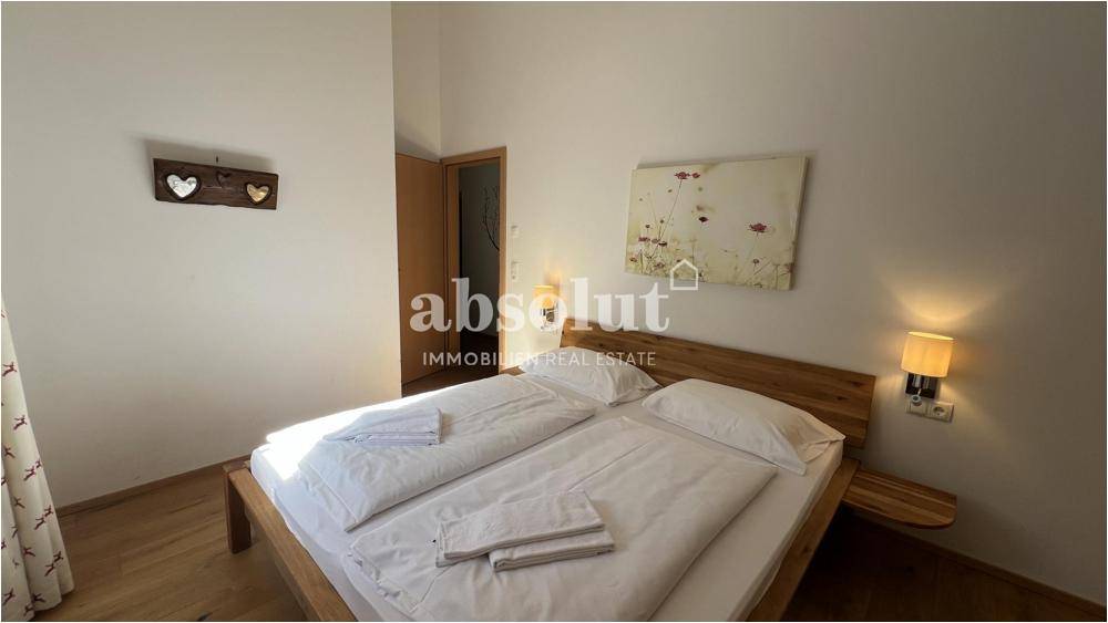 Gemütliches Schlafzimmer mit Doppelbett, Holzboden und schlichter Dekoration.