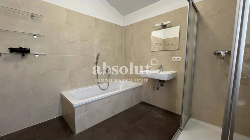 Geräumiges Badezimmer mit Badewanne, Duschkabine und Waschbecken, modern gefliest.