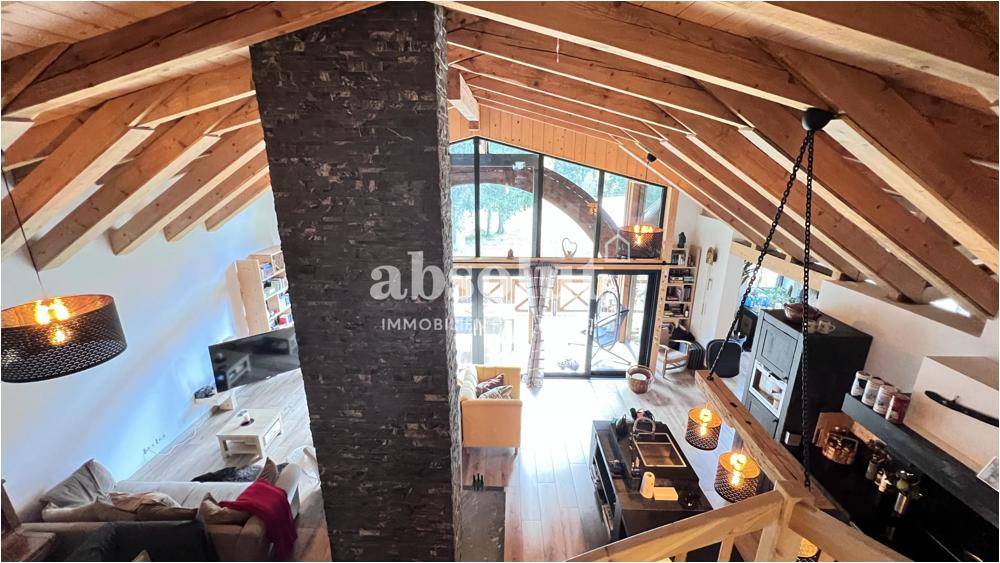 Geräumiger offener Wohnbereich mit hohen Holzdecken, Kamin und großen Fensterfronten.