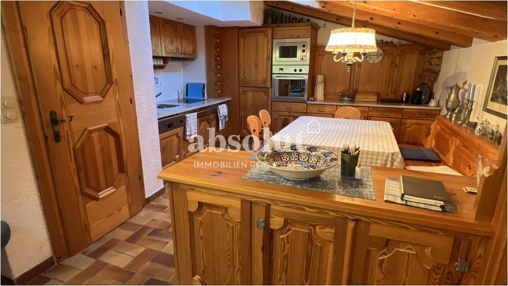 Gemütliche Holzküche mit integrierten Geräten und einem Essbereich, strahlt traditionellen Charme aus.