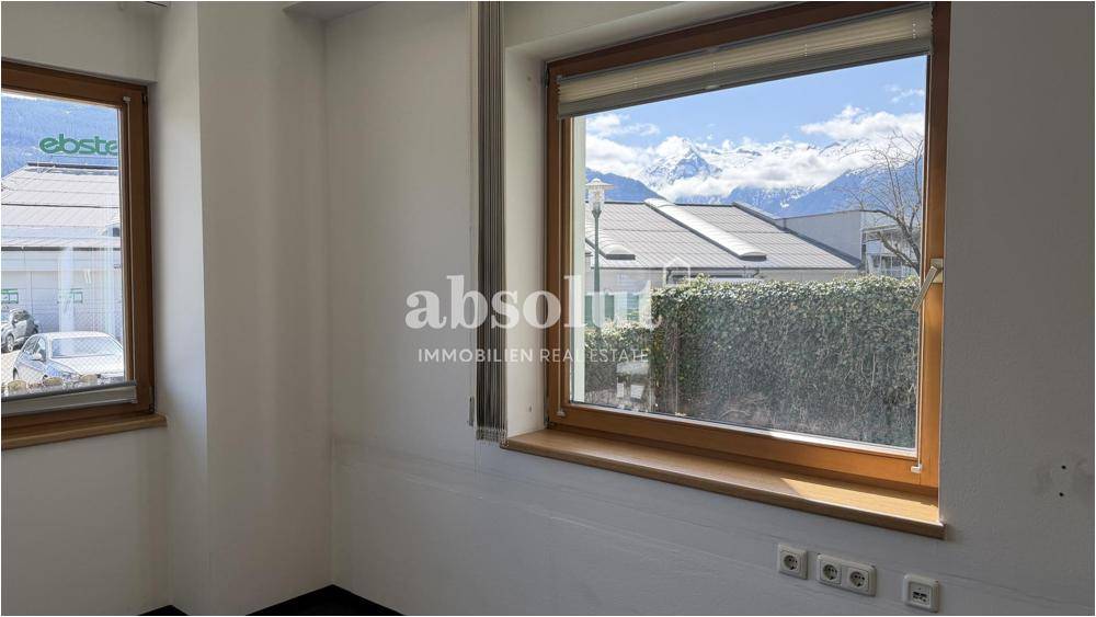 Helles Büro mit großen Holzfenstern und weitem Blick auf die schneebedeckten Berge.