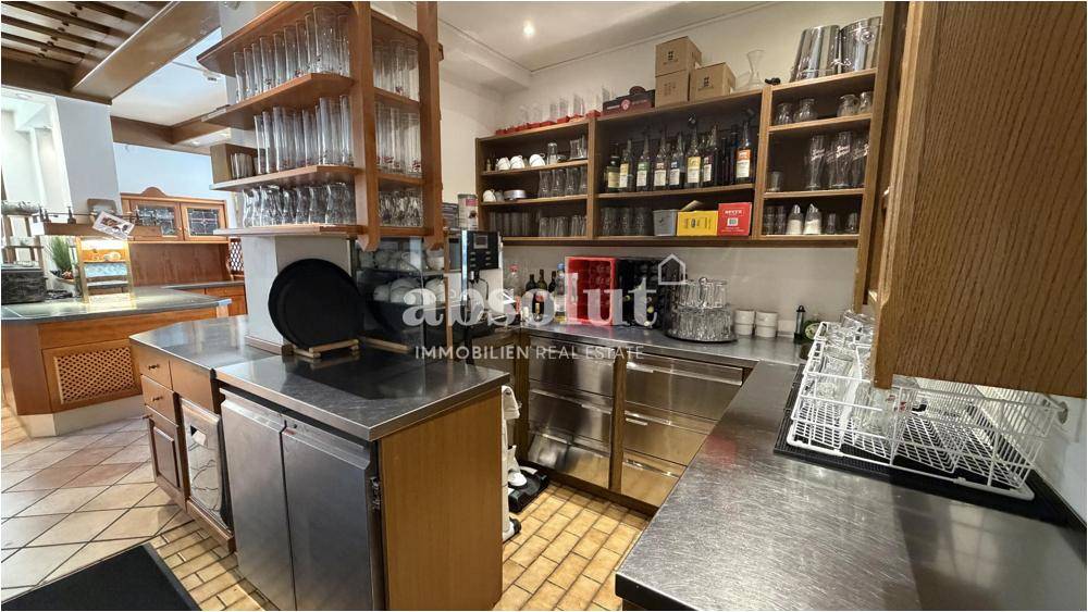 Professionelle Hotelküche mit Edelstahloberflächen, Regalen und gewerblichen Geräten.