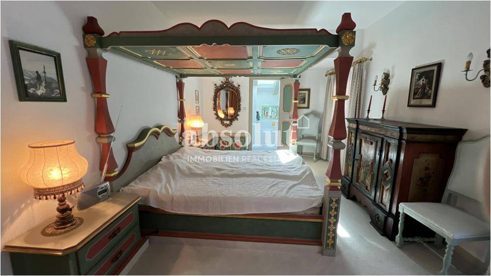 Geräumiges Schlafzimmer mit einem Himmelbett im traditionellen Stil und farbenfrohen Akzenten.