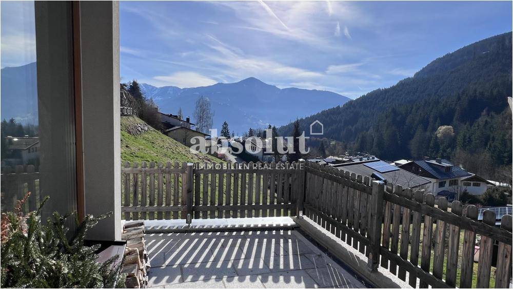 Weitläufige Terrasse mit Holzzaun und beeindruckendem Blick auf die umliegende Berglandschaft.