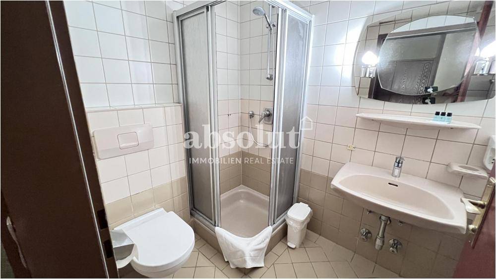 Kleines Badezimmer mit Duschkabine, WC und Waschbecken, ausgestattet mit hellen Fliesen.