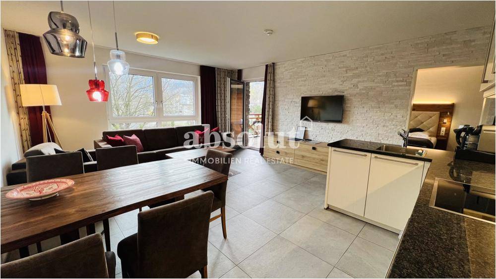 Gemütlicher Wohn-Essbereich mit Zugang zum Balkon, Fliesenboden und Steinwand.