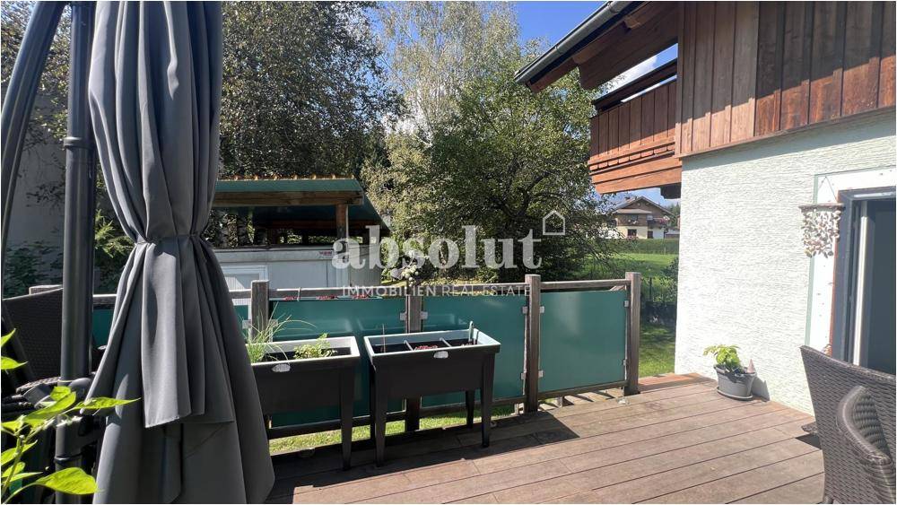 Einladende Holzterrasse mit Sonnenschirm und Pflanzen, perfekt für entspannte Stunden im Freien.
