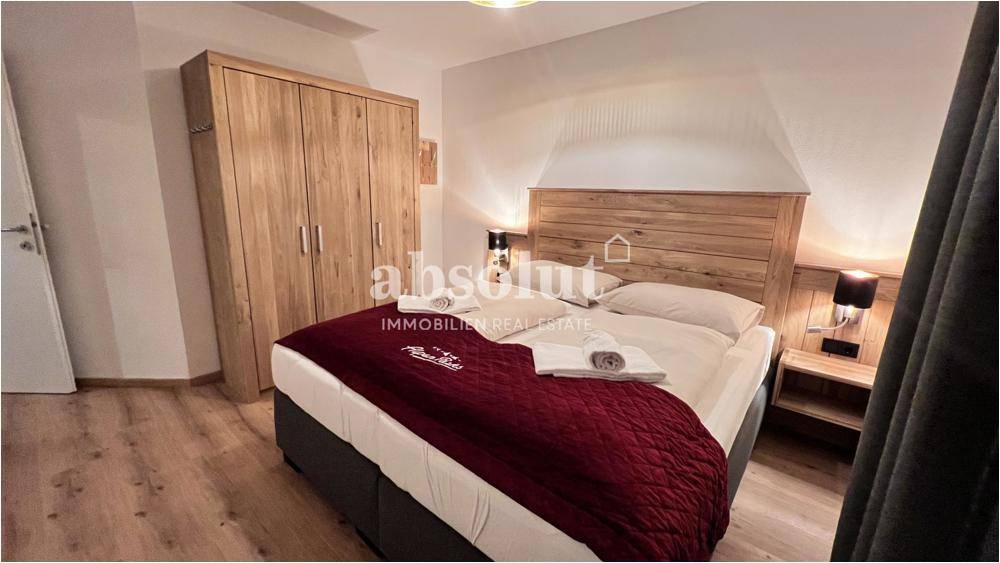 Schlafzimmer mit Doppelbett, großem Holzschrank und Holzboden in heller Ausführung für ausreichend Stauraum.