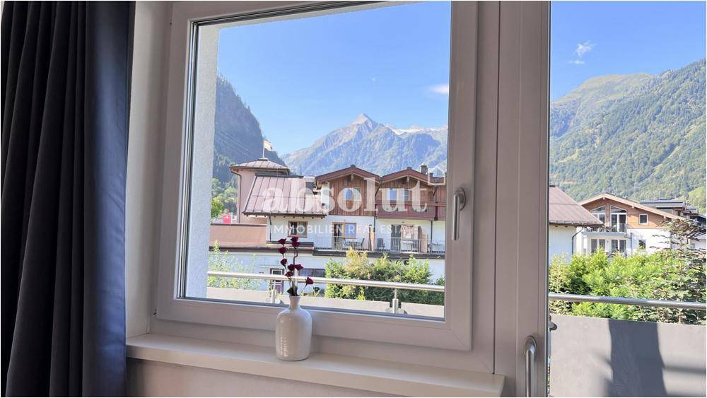 Fensterblick auf die beeindruckende Bergkulisse und die umliegenden Häuser der Region.
