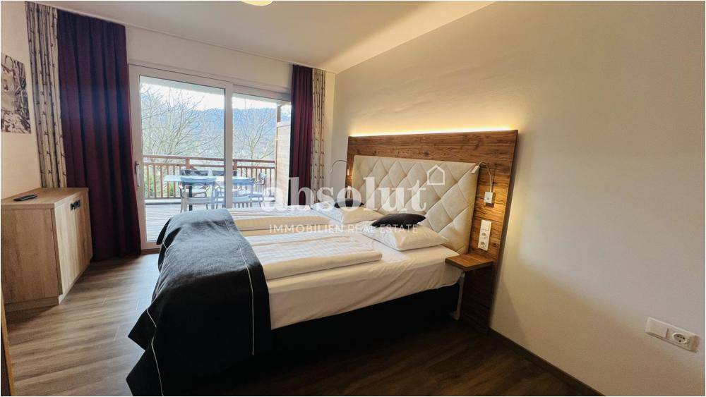Helles Schlafzimmer mit Doppelbett, Holzboden und direktem Zugang zum Balkon.