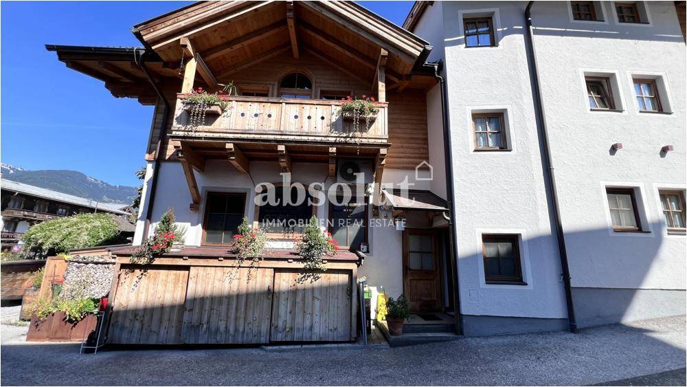 Nahaufnahme der traditionellen Holzfassade mit Balkon, Blumenkästen und einem einladenden Eingangsbereich.