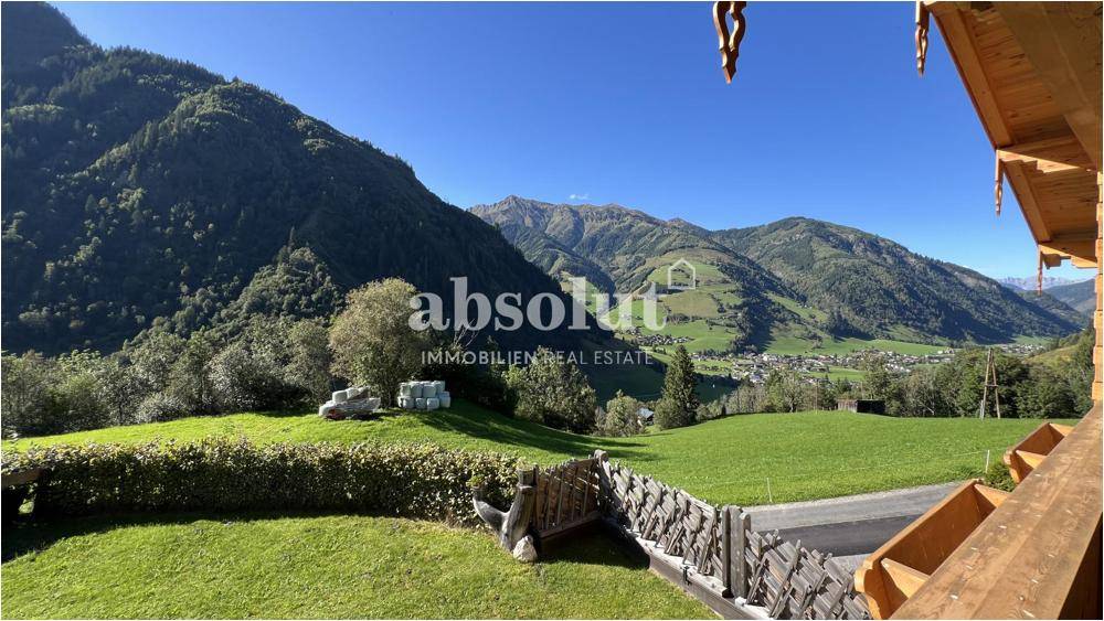 Weitläufiger Blick auf grüne Berge und ein malerisches Tal mit einem Dorf in der Ferne.