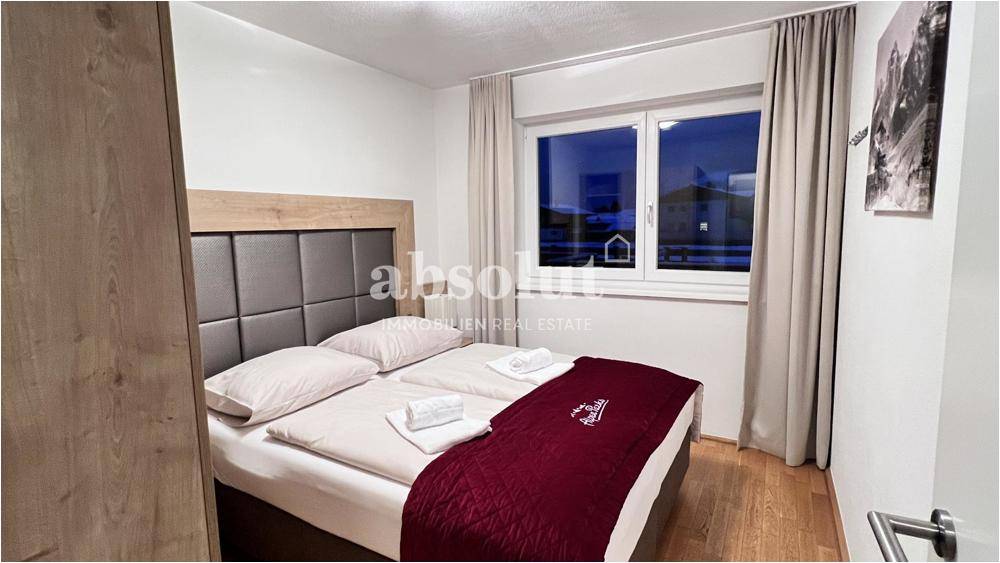 Helles Schlafzimmer mit Doppelbett, Holzboden und einem Fenster mit Blick nach draußen für erholsame Nächte.