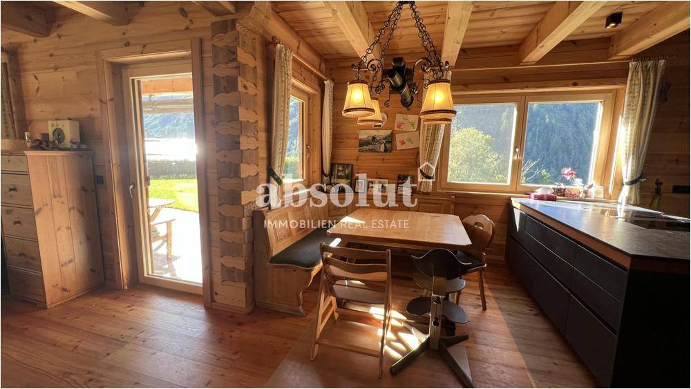 Heller Essbereich in der Holzküche mit Zugang zum Garten und traditioneller Sitzbank.