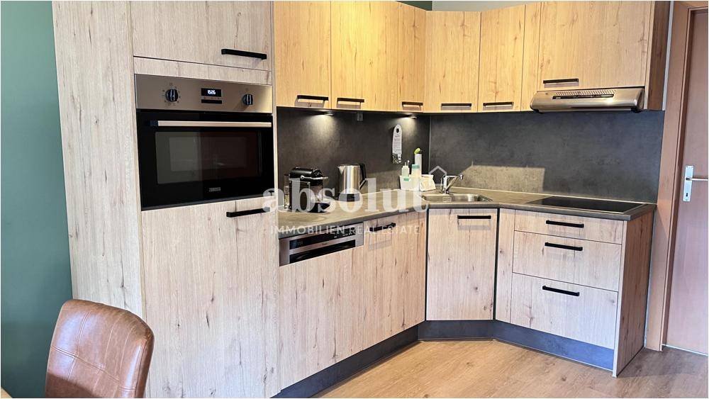 Moderne Einbauküche mit Holzfronten, integrierten Geräten und dunkler Arbeitsplatte.