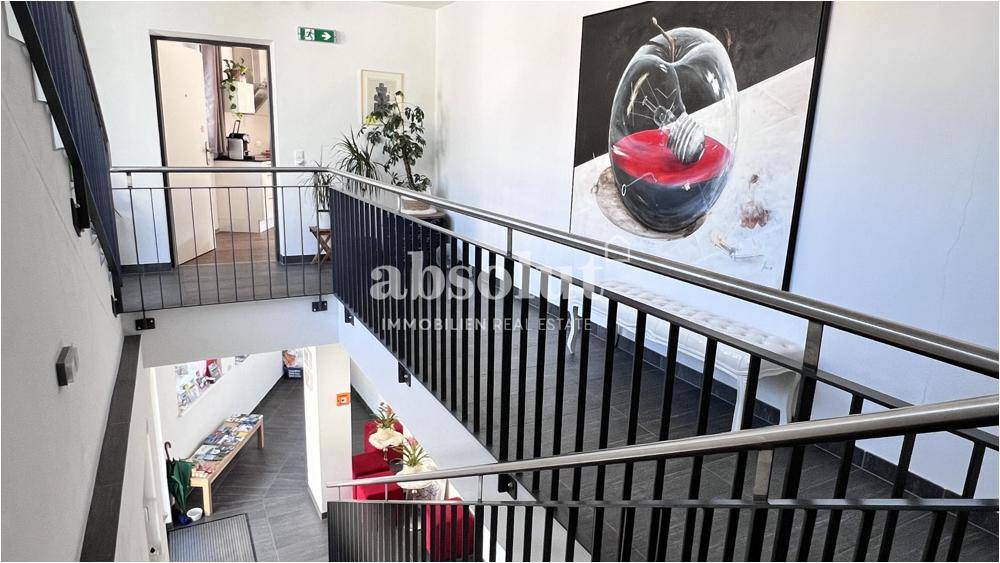 Geräumiges Treppenhaus mit Metallgeländer und moderner Kunst an den Wänden.
