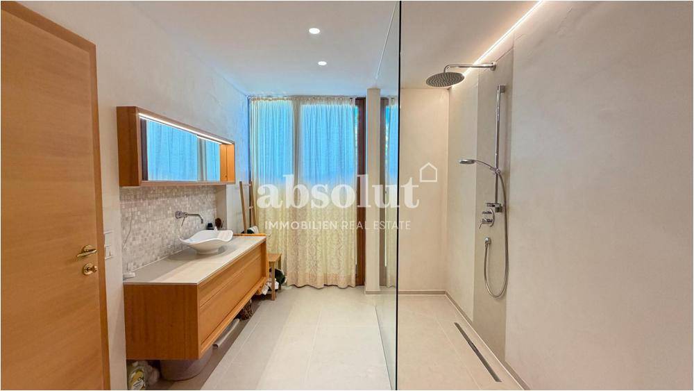 Modernes Badezimmer mit begehbarer Dusche, Einzelwaschbecken und indirekter Beleuchtung.