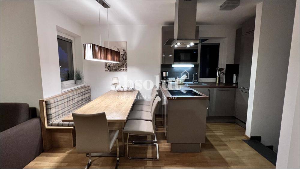 Moderne Küche mit Essbereich, integrierten Geräten und Holzboden in warmen Tönen für gesellige Mahlzeiten.