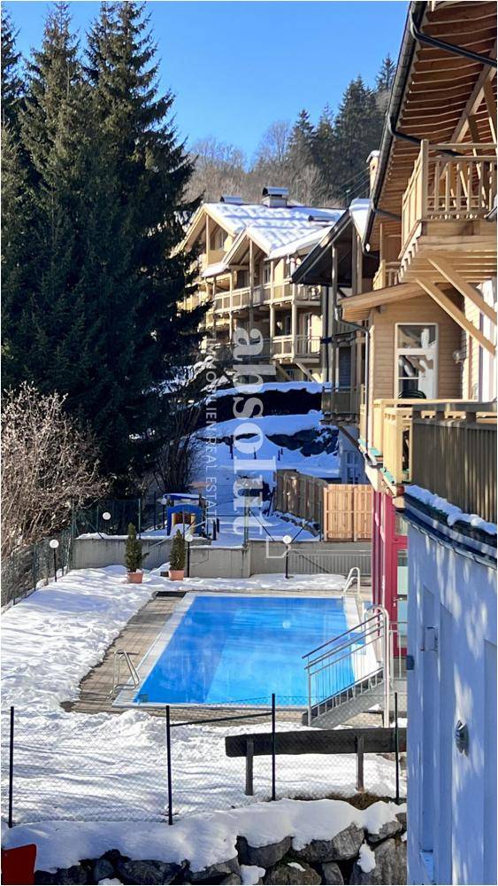 Außenpoolbereich im Winter mit verschneiter Umgebung und Blick auf die Gebäude.