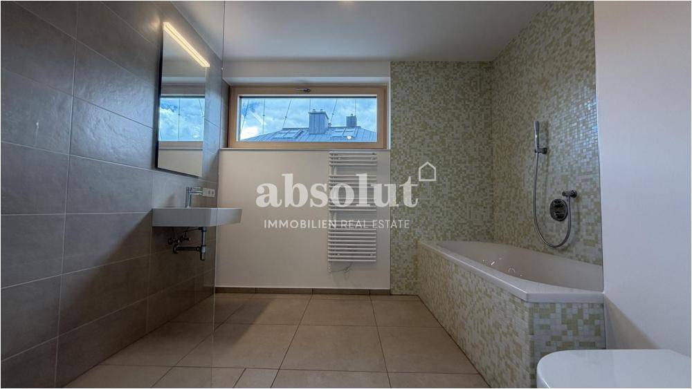 Modernes Badezimmer mit Badewanne, Duschbereich und beheiztem Handtuchhalter.