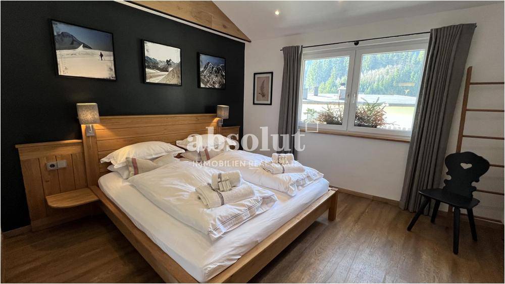 Gemütliches Schlafzimmer mit Doppelbett, Holzboden und Bergblick durch große Fenster.