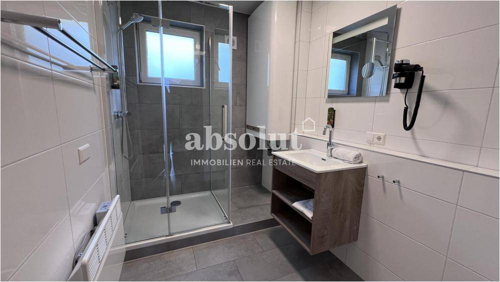 Modernes Badezimmer mit ebenerdiger Dusche, Einzelwaschbecken und hellen Fliesen.