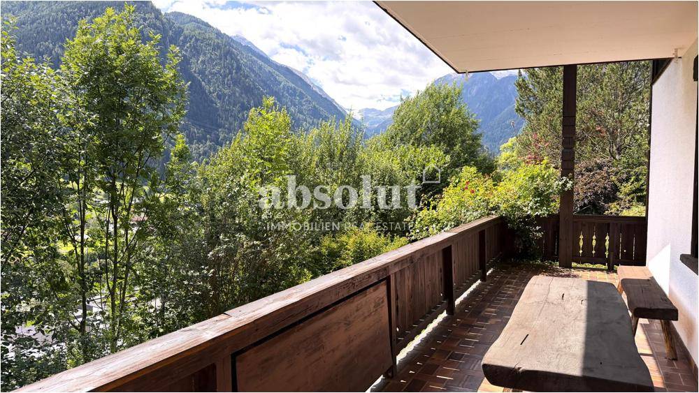 Geräumiger Balkon mit Holzboden und Sitzgelegenheiten, der einen atemberaubenden Panoramablick auf die Berge bietet.