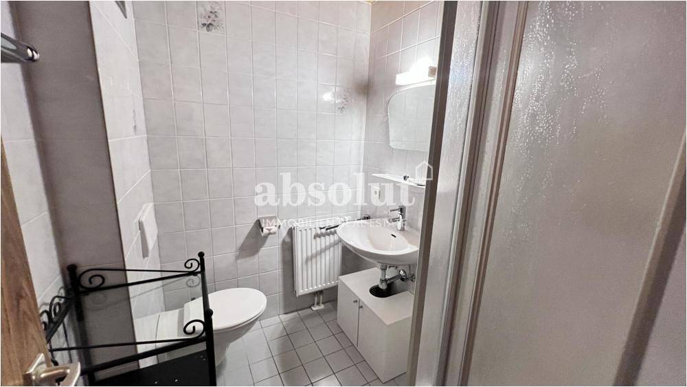 Helles Badezimmer mit Dusche, Waschbecken und WC, ausgestattet mit weißen Fliesen.