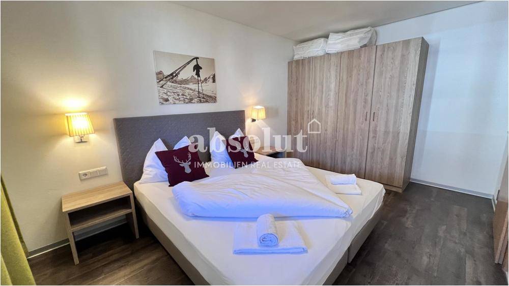 Schlafzimmer mit Doppelbett, Nachttischen und großem Holzschrank auf Laminatboden.