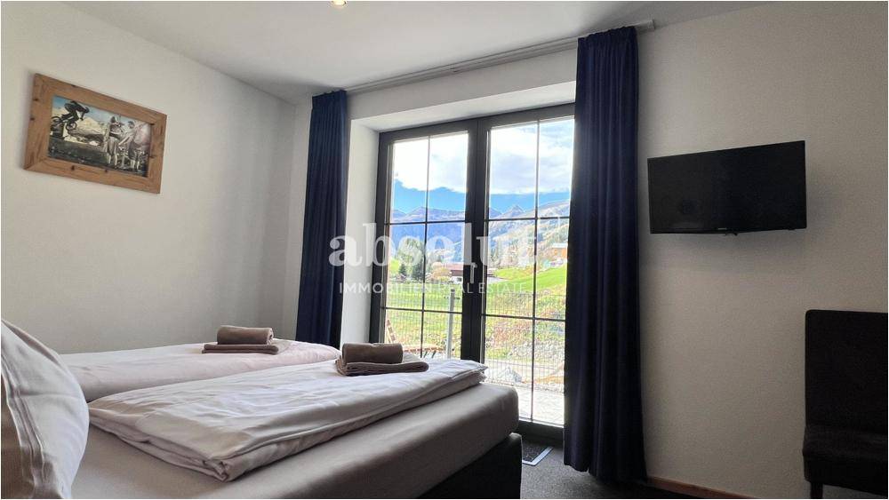 Gemütliches Schlafzimmer mit zwei Einzelbetten und Blick auf die grüne Berglandschaft.