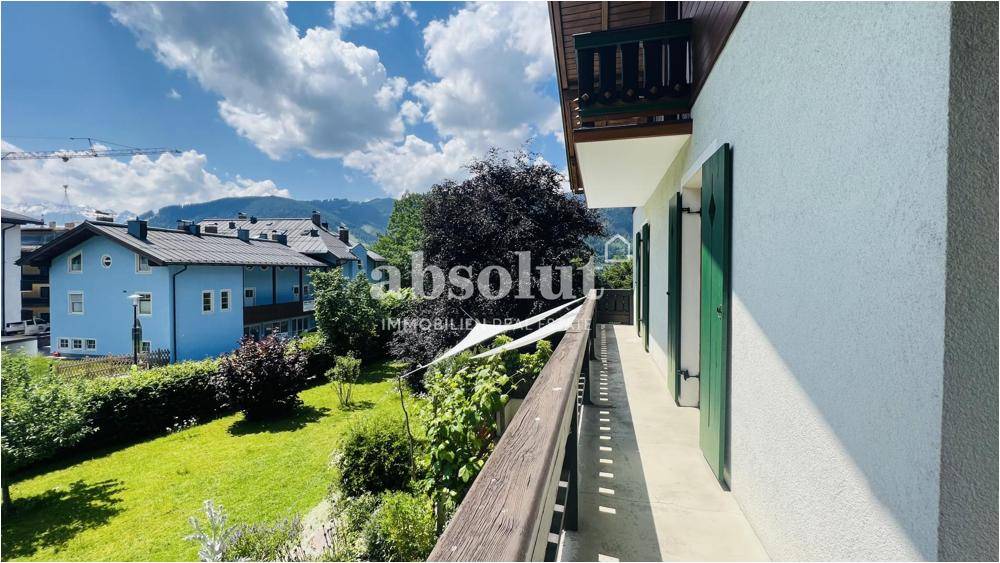 Langer Balkon mit Holzgeländer und weitem Blick über den Garten und die Umgebung.