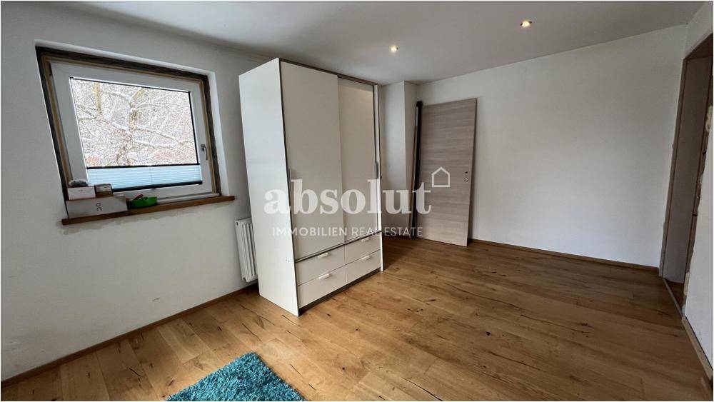 Helles Schlafzimmer mit Holzboden, Fenster und einem großen Kleiderschrank.