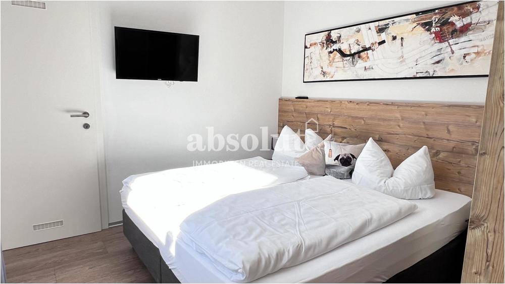 Komfortables Schlafzimmer mit Doppelbett, Holzkopfteil und moderner Wanddekoration.