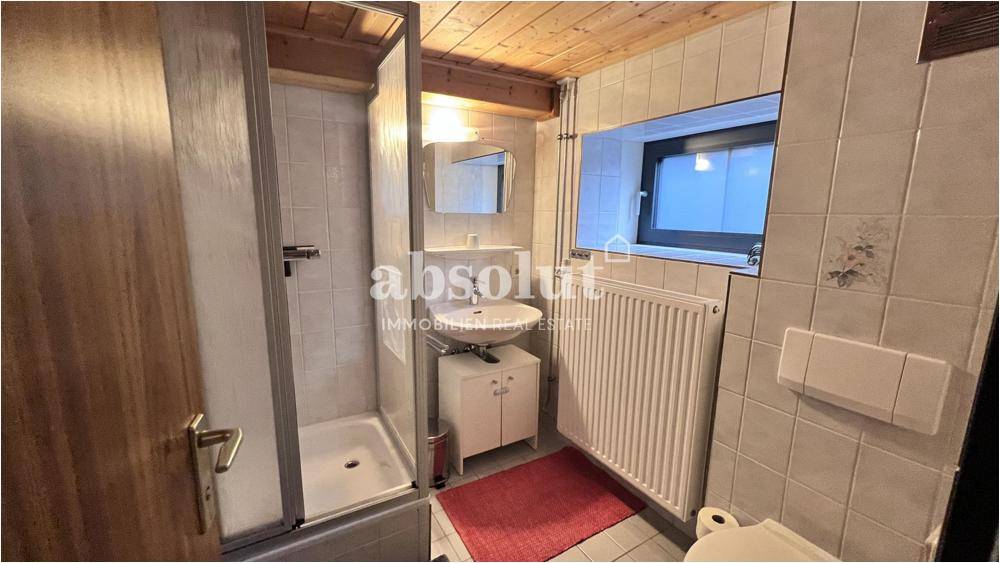 Funktionales Badezimmer mit Dusche, Waschbecken und Fenster für natürliche Belüftung.