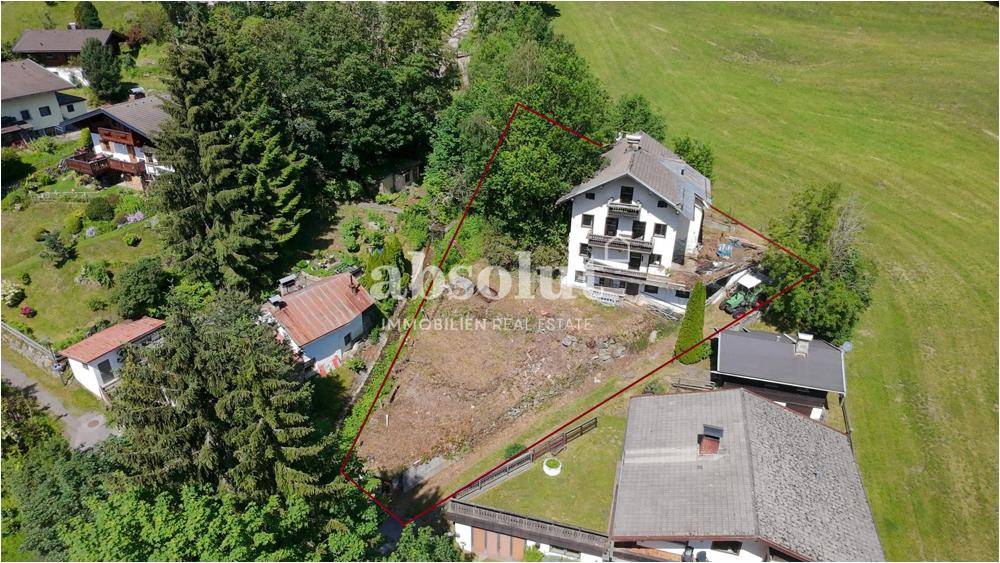Luftaufnahme eines Grundstücks mit einem Haus und umgrenztem Bereich in einer grünen Umgebung
