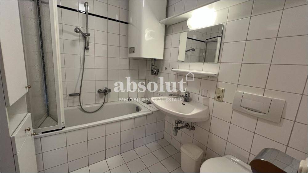 Gefliestes Badezimmer mit Badewanne, Duschfunktion, Waschbecken und WC, in einem funktionalen Design.