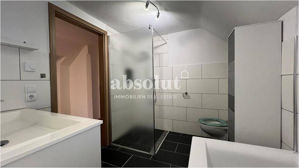 Badezimmer mit Duschkabine, Waschbecken und modernen Fliesen.