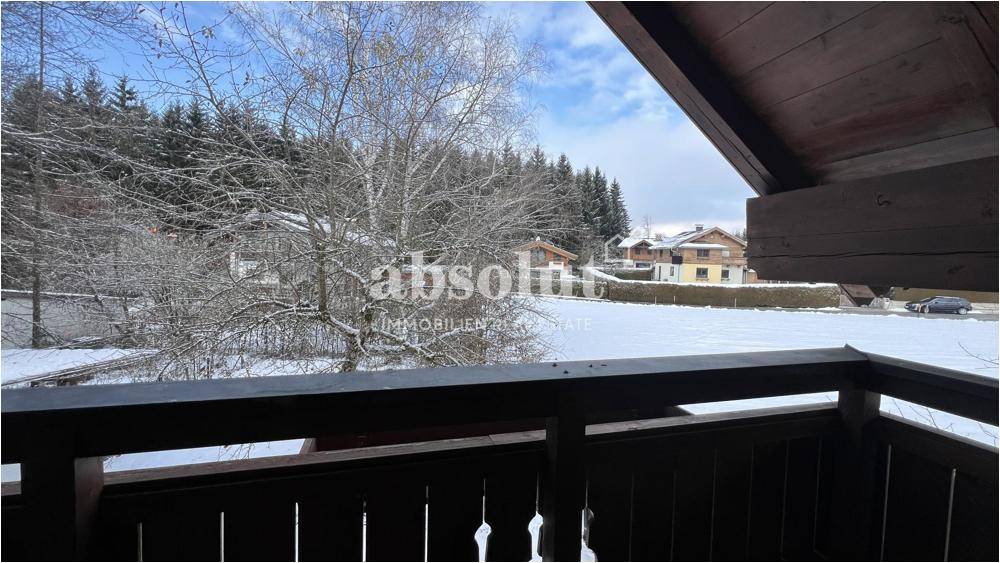 Balkon mit Blick auf eine verschneite Landschaft und umliegende Häuser.