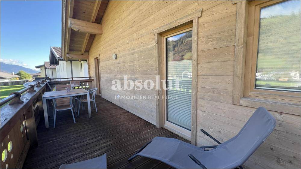 Langer Holzbalkon mit Sitzgelegenheiten und Zugang zu den Innenräumen.