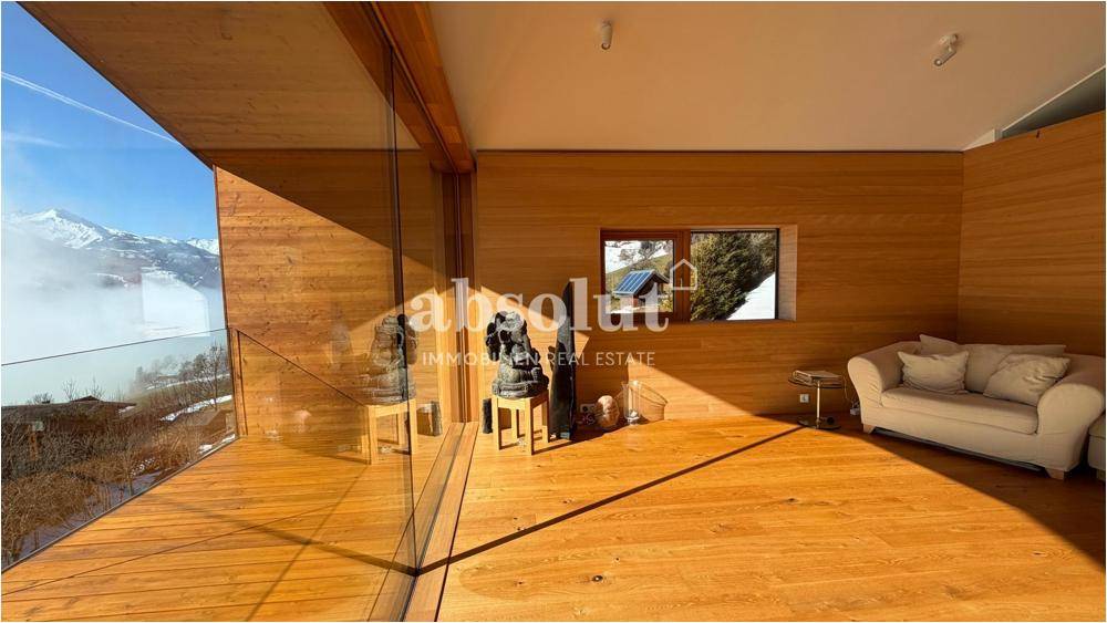 Geräumiges Wohnzimmer mit Holzboden, bequemer Couch und Panoramablick auf die verschneiten Berge.