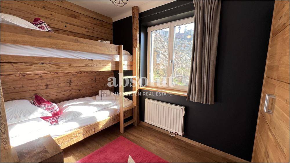 Rustikales Schlafzimmer mit Etagenbett und Holzverkleidung, ideal für Kinder oder Gäste.